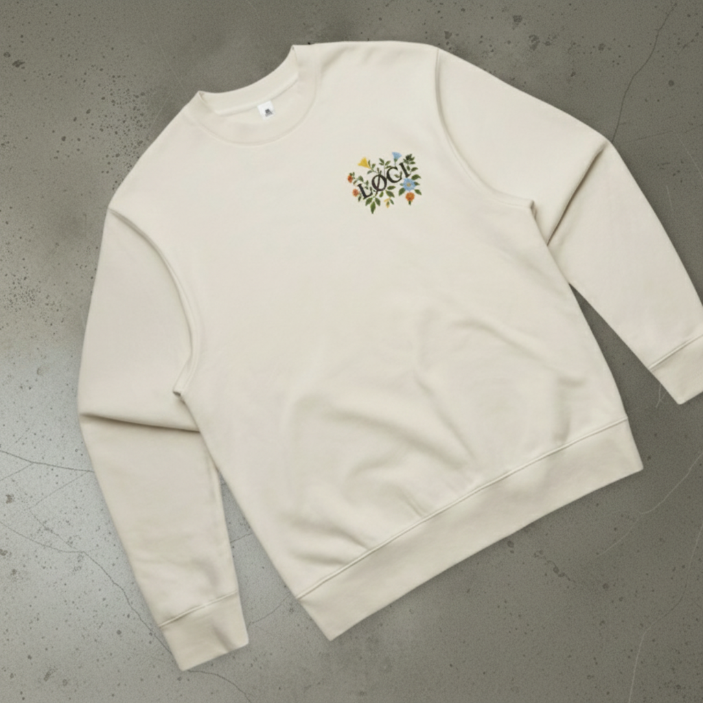 Beige sweatshirt with a colorful logo on a gray concrete floor