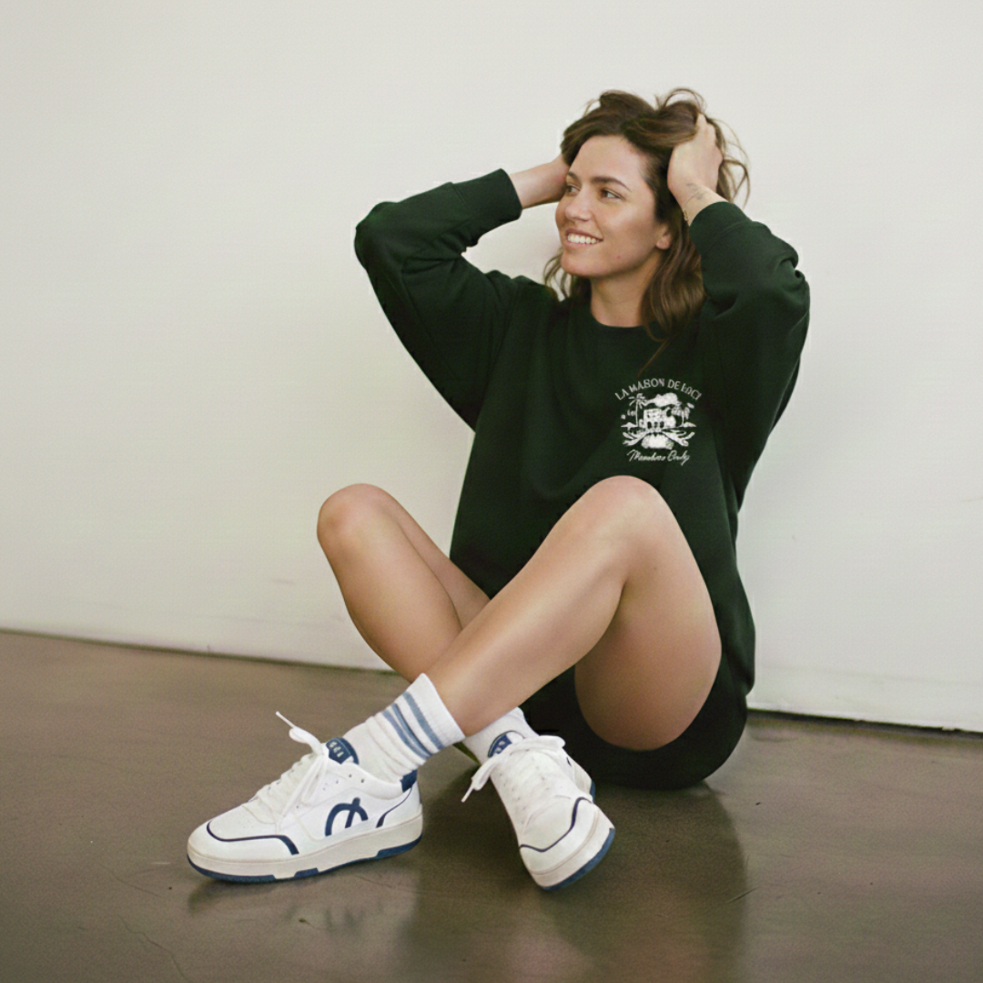 Seated model in a green LØCI hoodie and sneakers